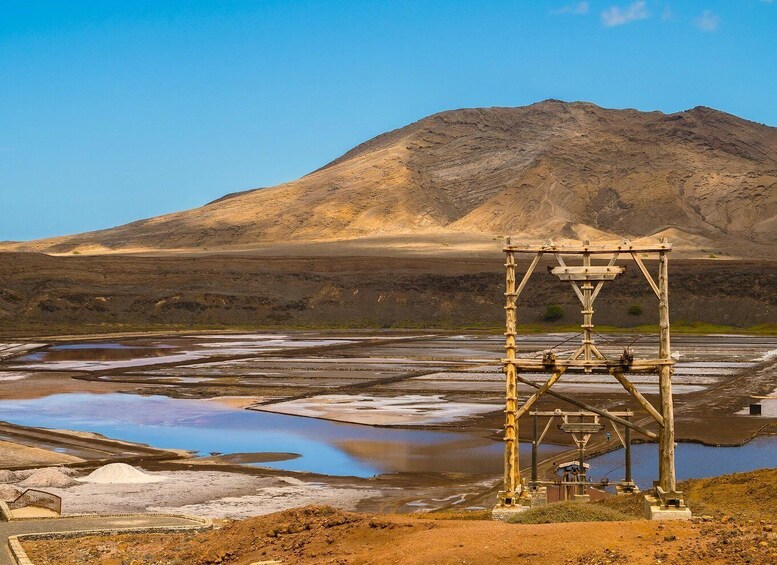 A salt flat with a wooden structure in the foreground and a mountain in the background. 4