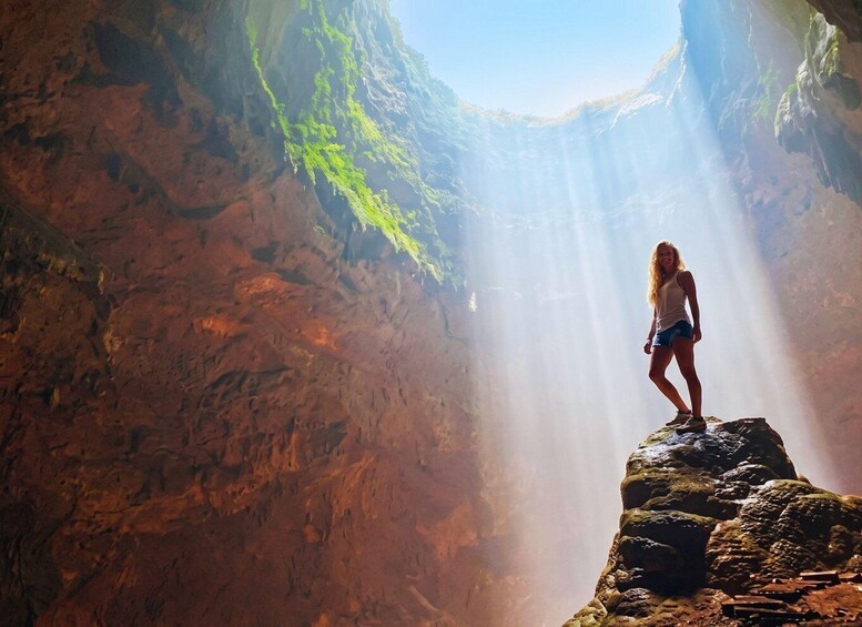 Una persona de pie sobre una roca en un cañón, con rayos de sol iluminando el paisaje. 5