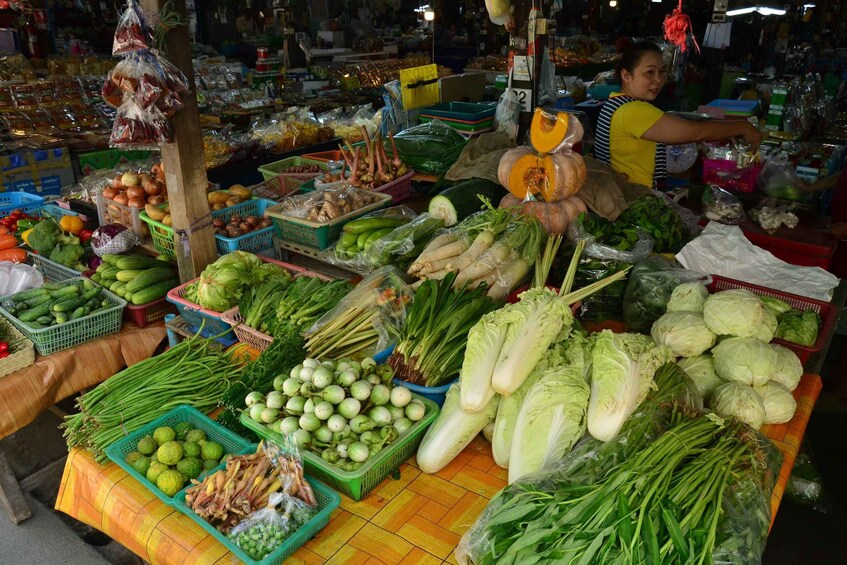 A market stall with various vegetables and fruits, including cabbages, cucumbers, and green onions. 5