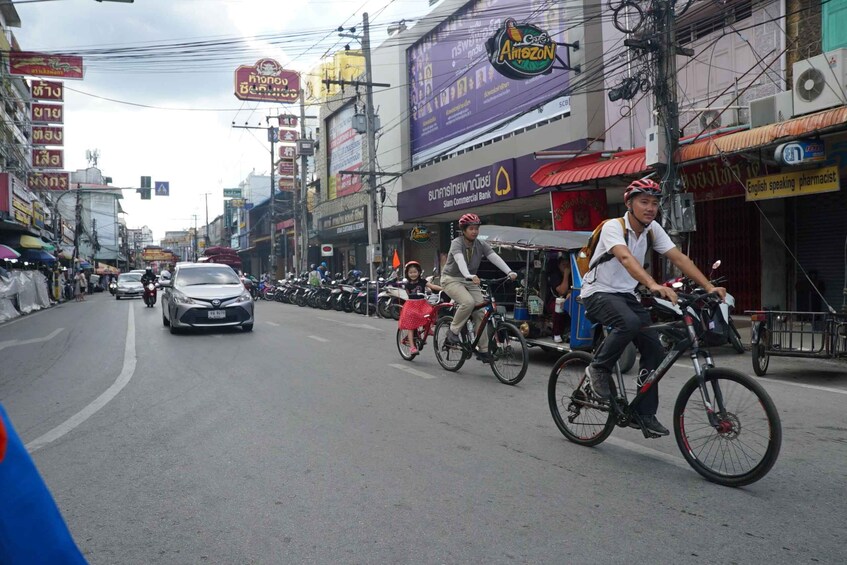 A busy street with multiple cyclists, parked motorcycles, and various commercial buildings. 4