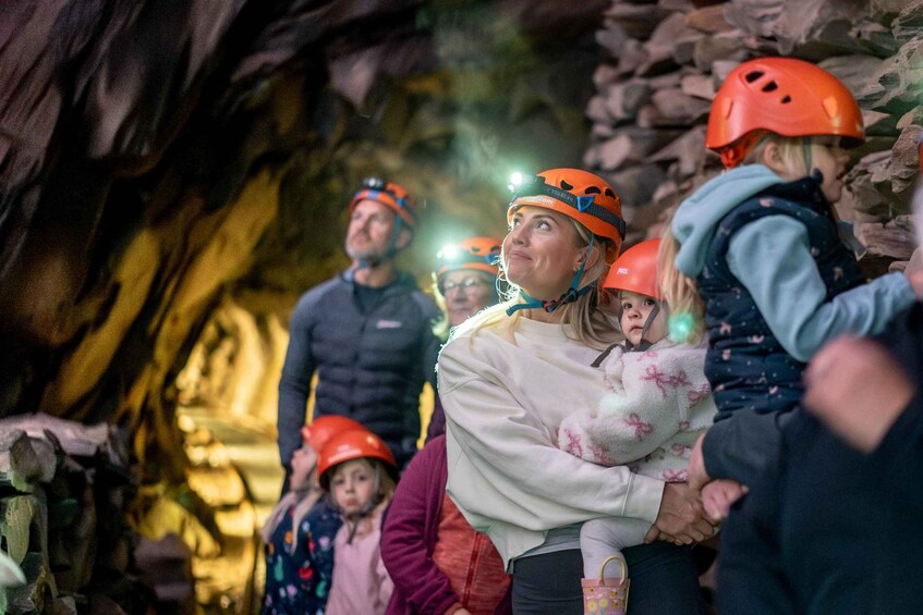 A group of people in a cave with helmets and headlamps. 1