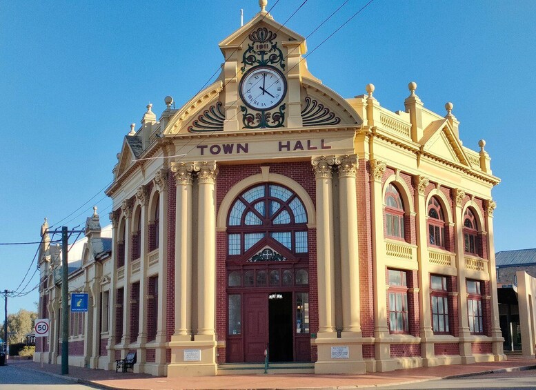 A town hall with a clock, arched windows, and a sign indicating tourist information. 5