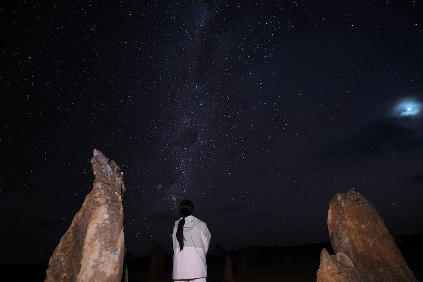 A person standing between two rock formations under a starry night sky. 3