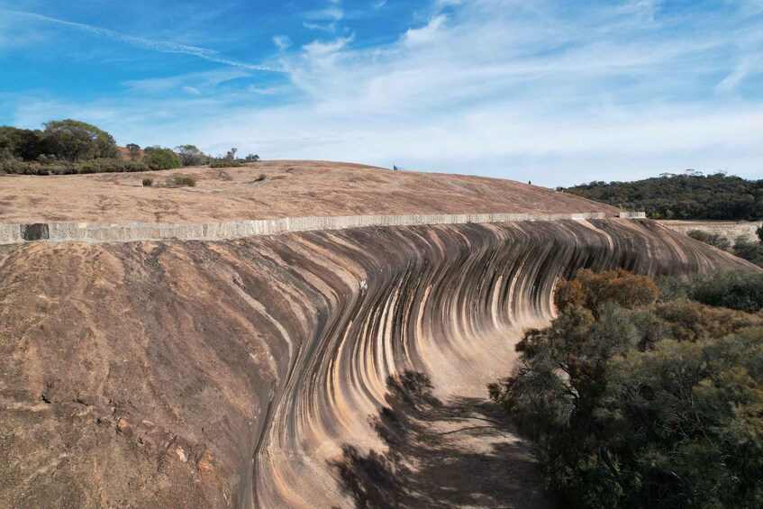 A dry, undulating landscape with a concrete retaining wall and sparse vegetation. 3