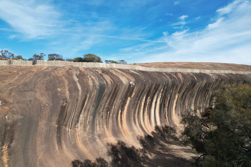 A large, curved geological formation with a clear sky above. 2