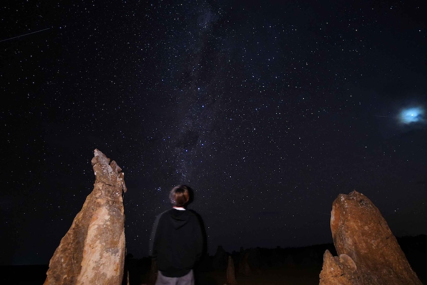 A person standing between two rock formations under a starry night sky. 5