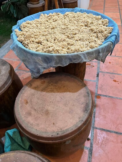 A blue cloth-covered container filled with grains on a terracotta pot. 1