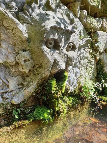 A rock formation with carved faces and a small cave entrance. 3