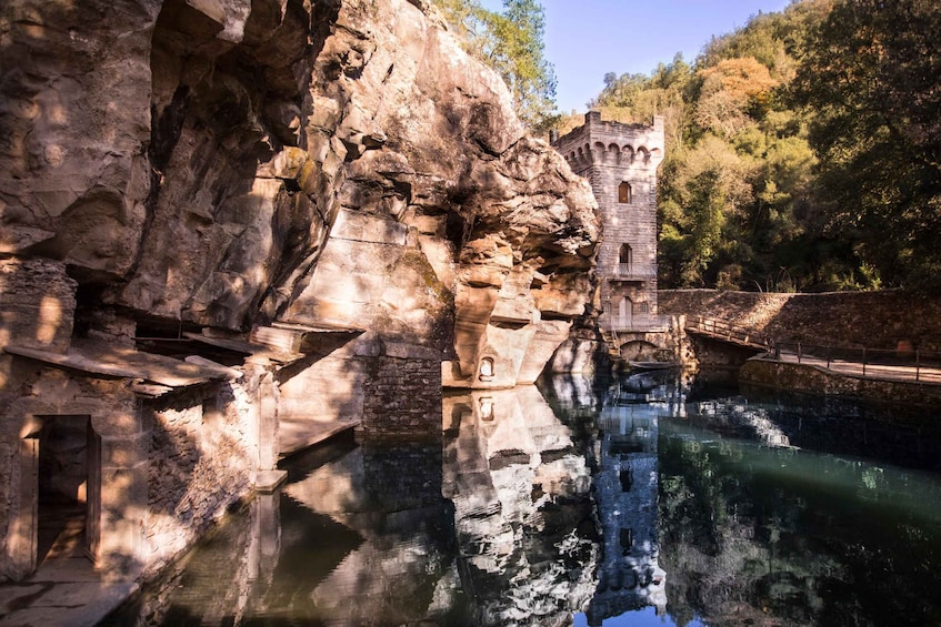 A historic stone bridge over a clear river, with a castle in the background. 5