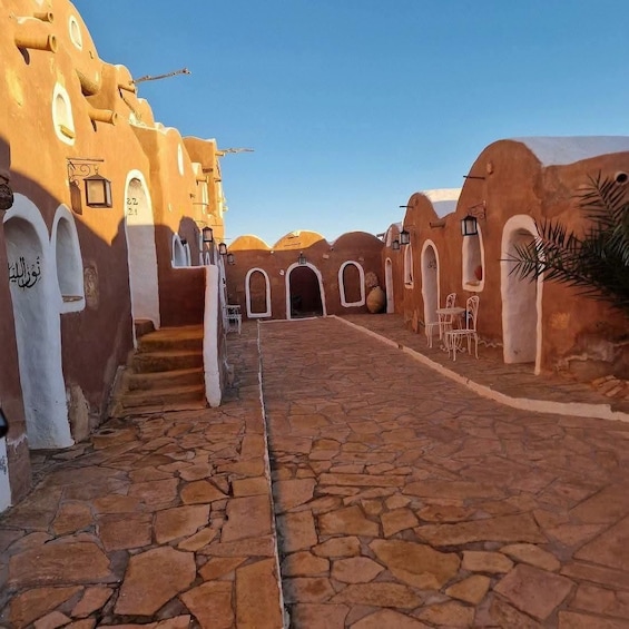 A cobblestone courtyard with arches and a staircase leading up to a building. 2