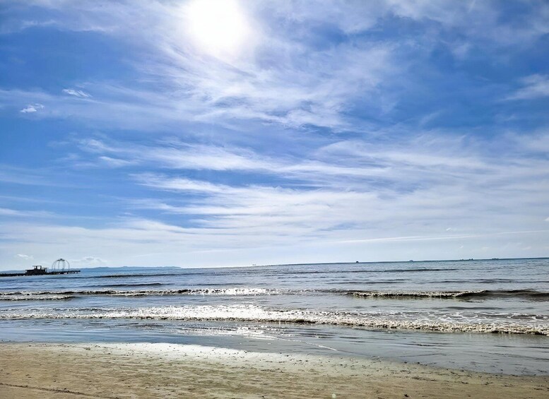 A beach with waves, a pier, and a clear sky. 5