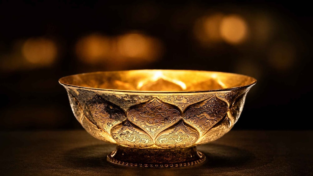 A golden bowl with intricate patterns, placed on a dark surface. 2