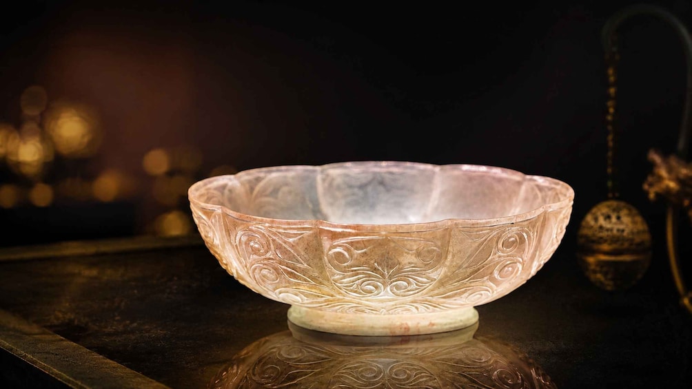 A clear glass bowl with intricate designs on a reflective surface. 1