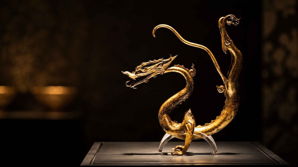 A golden dragon sculpture on a stand. 3