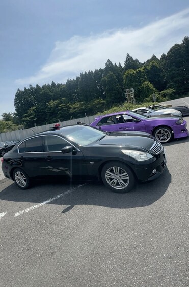 Pysäköintialue, jossa on musta neliovinen auto ja violetti auto. 4
