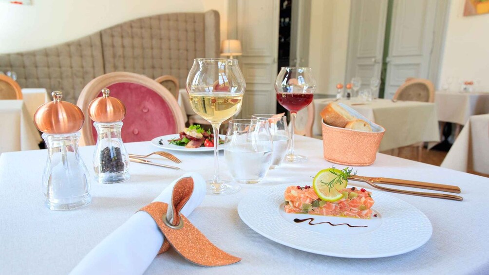 A table set for a meal with a plate of salmon tartare, glasses of white and red wine, and a bread basket. 2