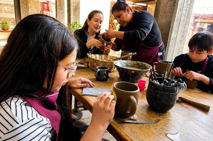 A group of people engaged in pottery making at a table with various pottery tools and materials. 2