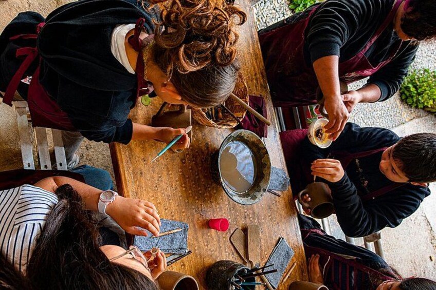 A group of people sitting around a wooden table, engaged in a craft activity involving scissors and paper. 3