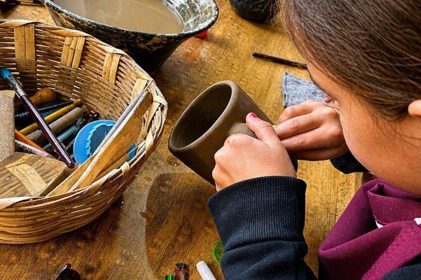 A person shaping a clay pot on a wooden table. 1
