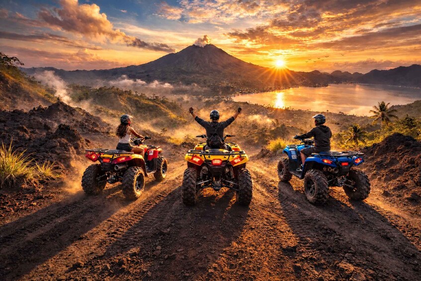 Three people on all-terrain vehicles on a dirt path with a volcano and a lake in the background. 4