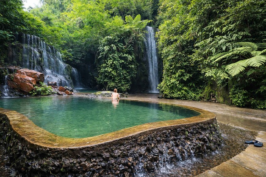 A natural hot spring surrounded by waterfalls and dense forest. 5