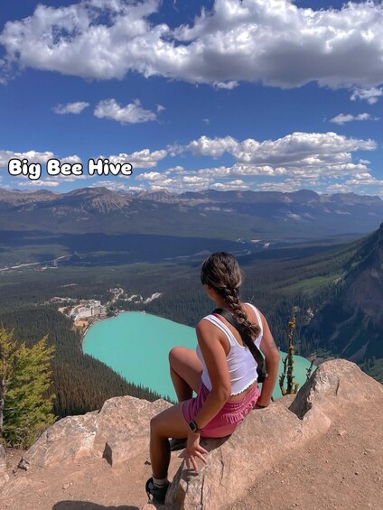 A person sitting on a rock overlooking a turquoise lake with mountains in the background. 3