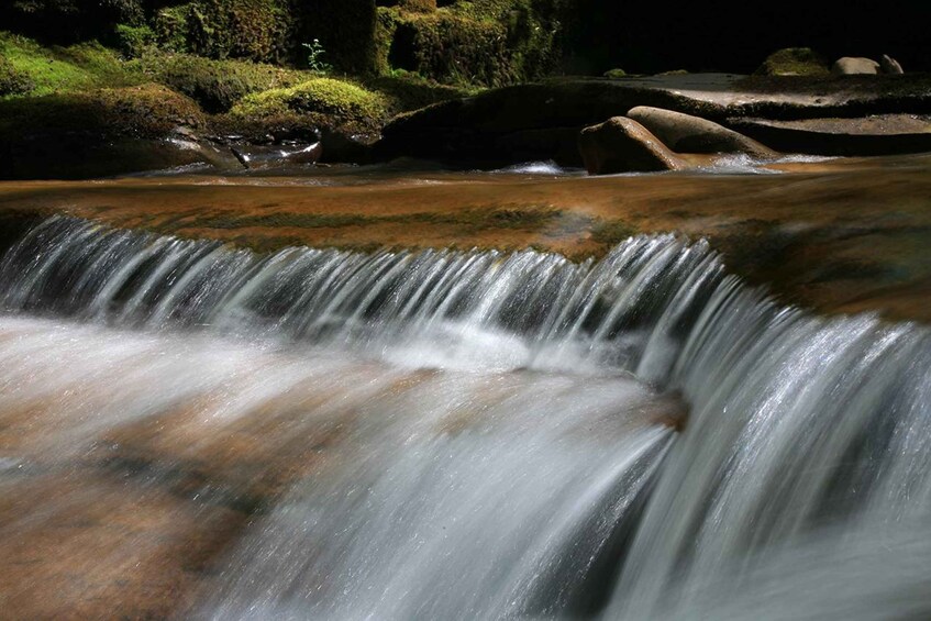 A waterfall cascading over rocks in a forested area. 3