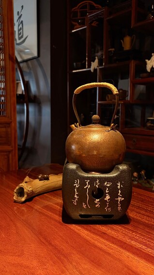 A traditional copper teapot with a wooden base, placed on a wooden table in a room with a dark ambiance. 3