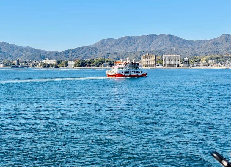 A ferry moving across a calm body of water with mountains in the background. 3