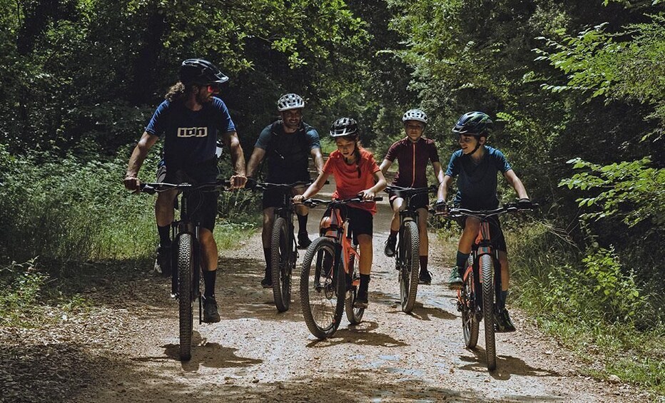 A group of cyclists on a dirt trail surrounded by dense greenery. 2
