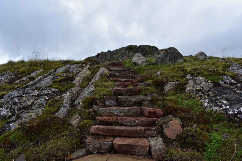 A stone staircase leading up a grassy hill with rocky outcrops. 4