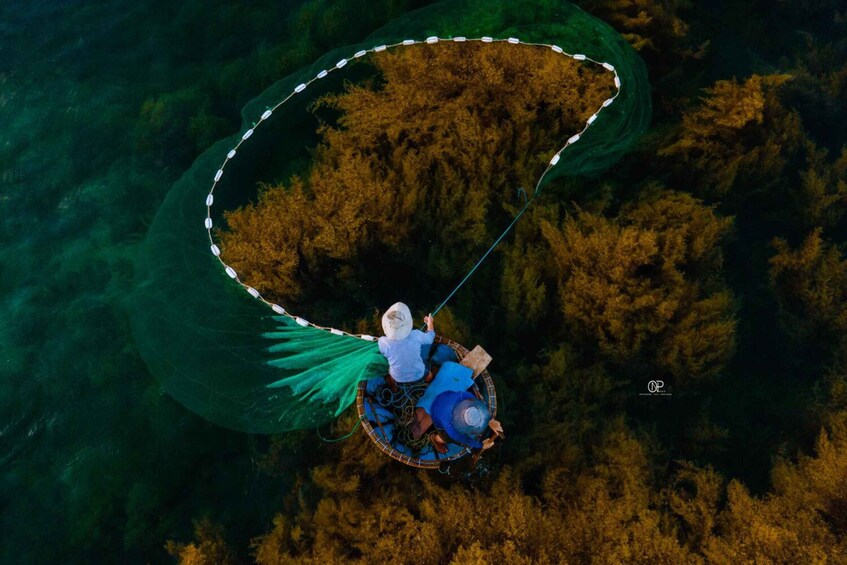 An aerial view of a person in a boat with a green canopy, surrounded by dense forest and water. 1