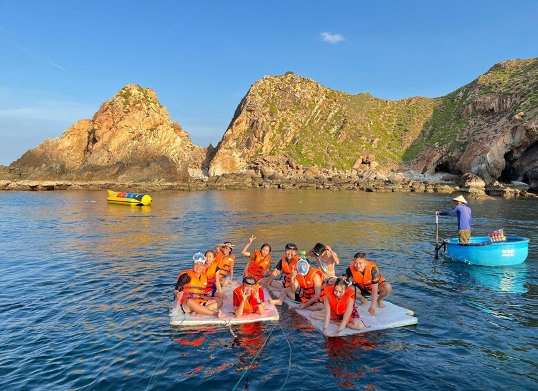 A group of people on a raft in a body of water with rocky cliffs in the background. 4