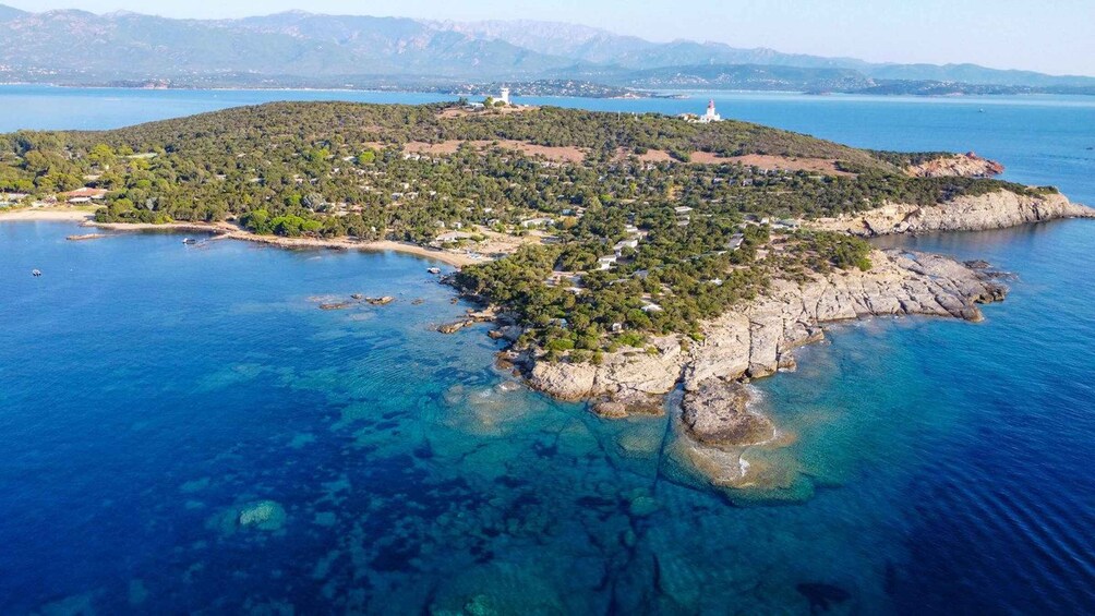 An aerial view of a coastal island with clear blue waters, rocky shores, and scattered buildings. 4
