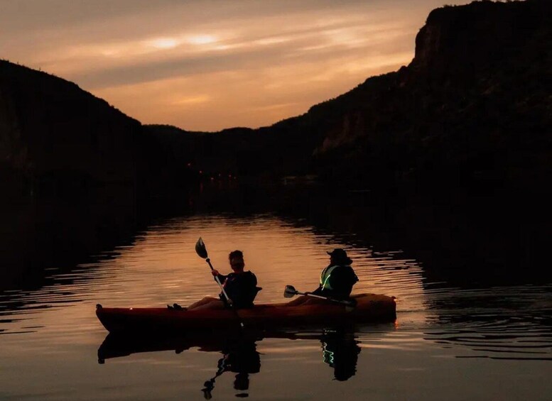 Two people kayaking on a calm river at sunset. 2
