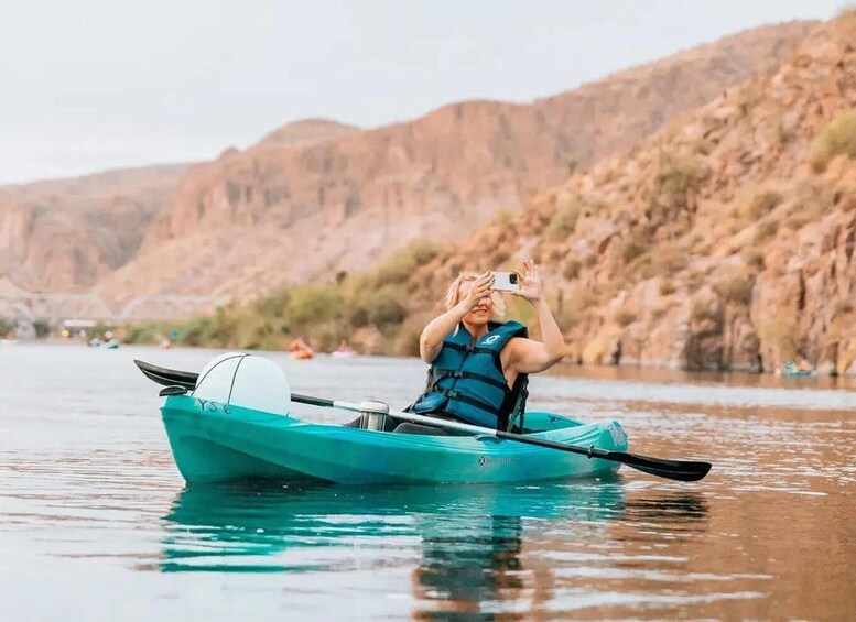 A person kayaking on a calm river with mountains in the background. 3