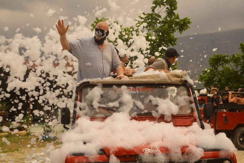 A red vehicle with foam being sprayed at it, surrounded by people. 5
