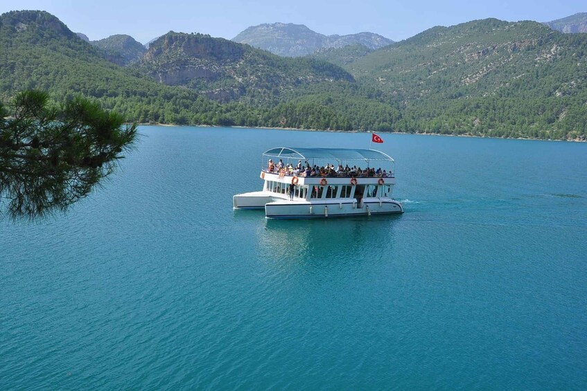 A boat with passengers on a lake surrounded by mountains. 3