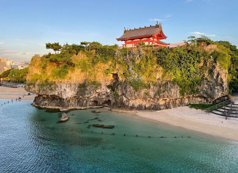 A traditional red building on a cliff by a clear beach. 3