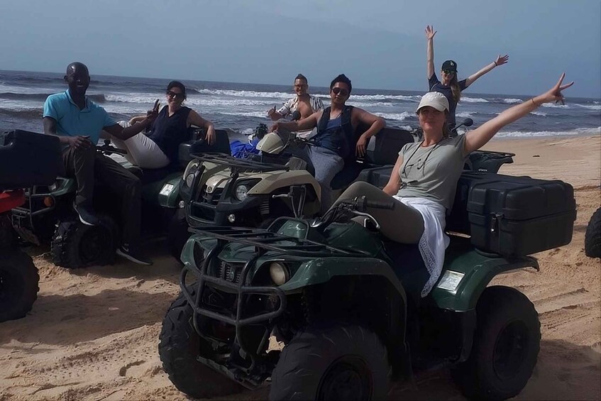 A group of people on ATVs on a beach with the ocean in the background. 2