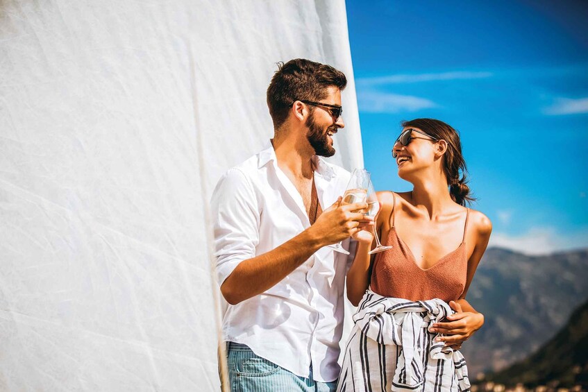 A couple on a sailboat with a mountainous landscape in the background. 2