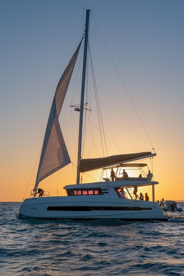 A sailboat with a crew at sunset. 1