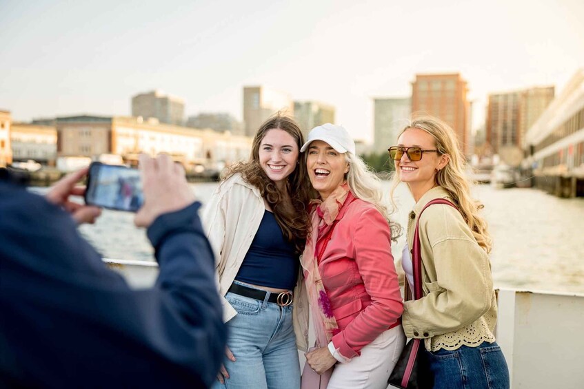 Three people taking a selfie on a rooftop with a cityscape in the background. 1