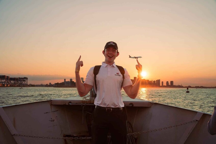A person on a boat pointing towards a sunset with a city skyline in the background. 5