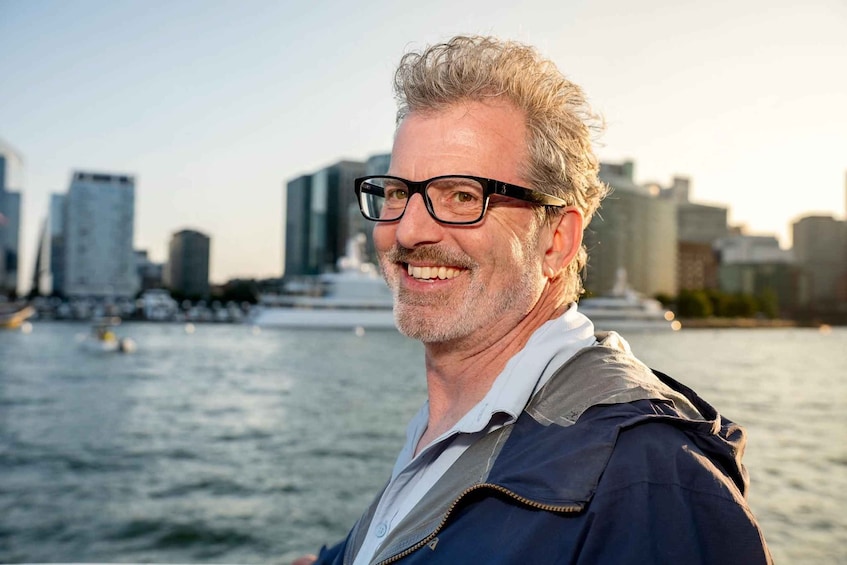 A person standing on a boat with a city skyline in the background. 4