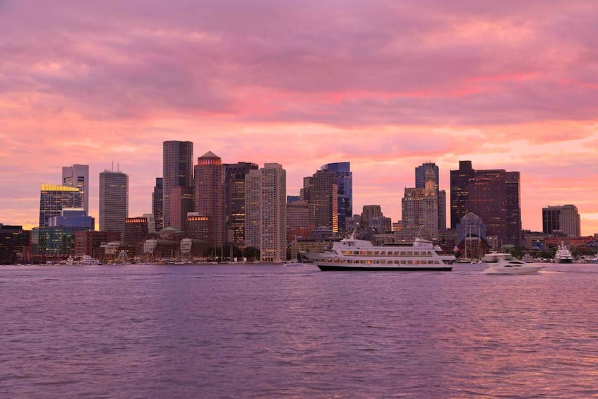 A city skyline at sunset with a cruise ship in the foreground. 1