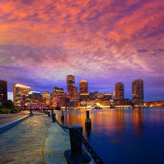 A city skyline at dusk with illuminated buildings reflecting on the water. 2