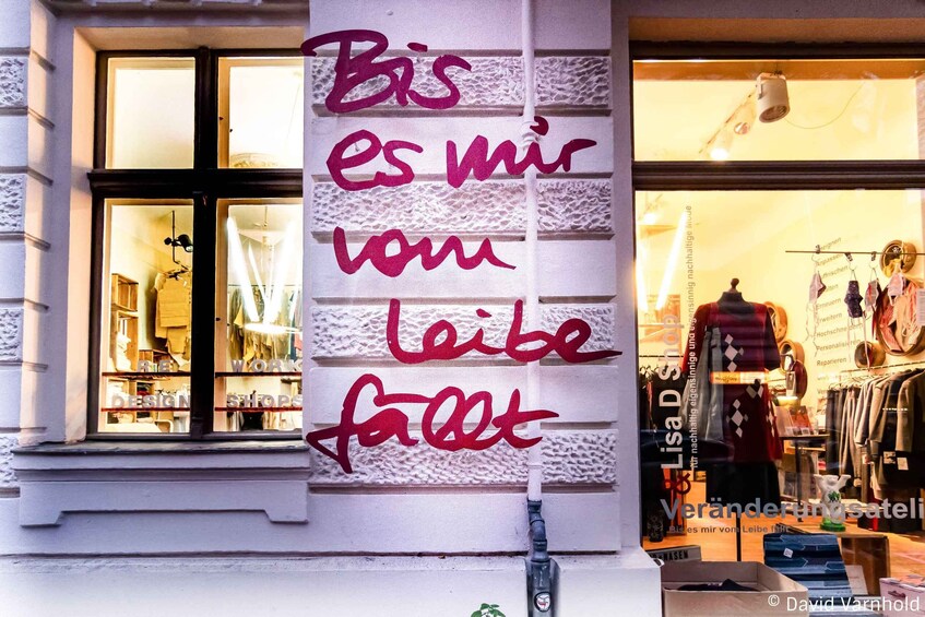 A storefront with a sign in German, 'Bis es mir vom Leib fällt,' and a mannequin in the window. 3