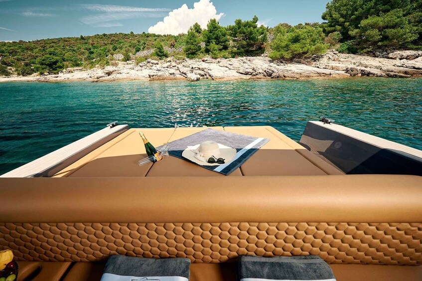 A boat's interior with a view of a rocky shoreline and clear blue water. 1