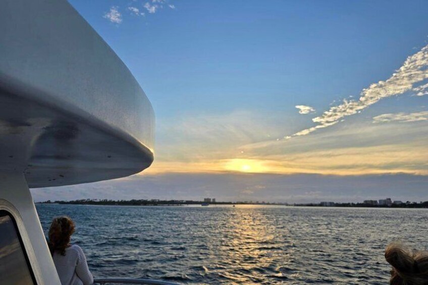 A sunset over a body of water with a boat and a person in the foreground. 5